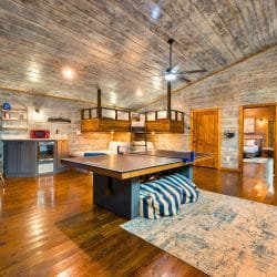 Game house with a ping pong table, an arcade cabinet, a bunk loft above and a kitchenette against a gray wood wall