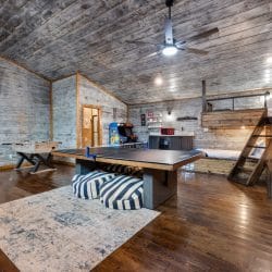 Game house with a ping pong table, foosball, arcade cabinets and a bunk loft under a gray wood ceiling
