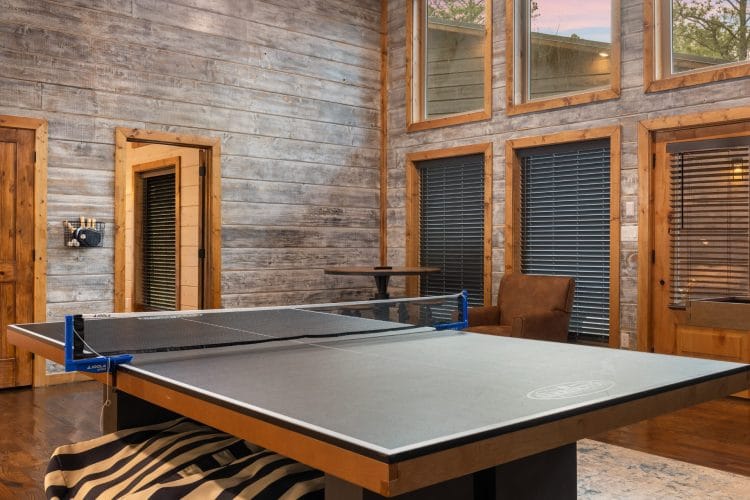 Ping pong table on a zebra rug with tall windows in the game house