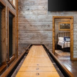 Shuffleboard table with a TV above it and a doorway into a bedroom
