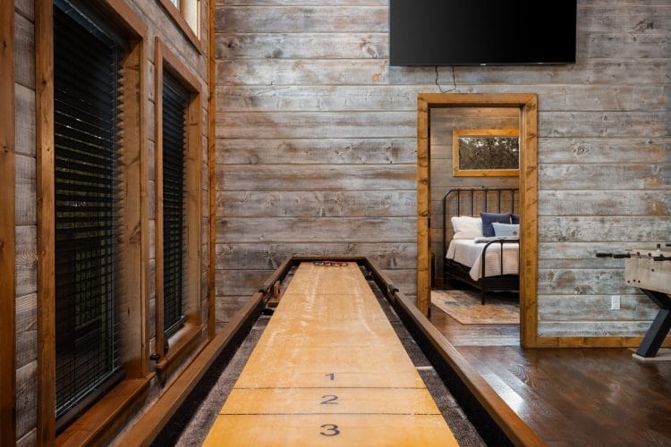 Shuffleboard table with a TV above it and a doorway into a bedroom