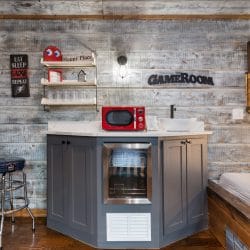 Kitchenette with gray cabinets, a mini fridge and a red microwave, with a bunk bed beyond
