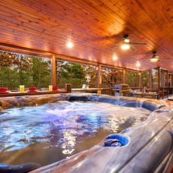 Hot tub on the covered deck beside a bar-height counter, under a pine ceiling