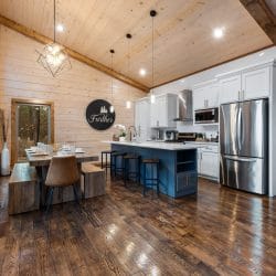 Kitchen with white cabinets, a navy island with bar stools and a stainless refrigerator