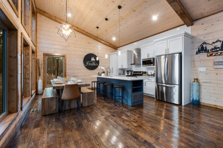 Kitchen with white cabinets, a navy island with bar stools and a stainless refrigerator
