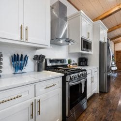 Kitchen with white cabinets, a stainless range and hood, and a spice rack