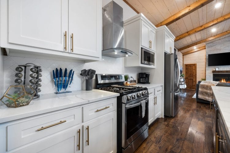 Kitchen with white cabinets, a stainless range and hood, and a spice rack