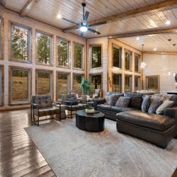 Living room with a gas fireplace, a dark leather sectional and a wall of tall windows
