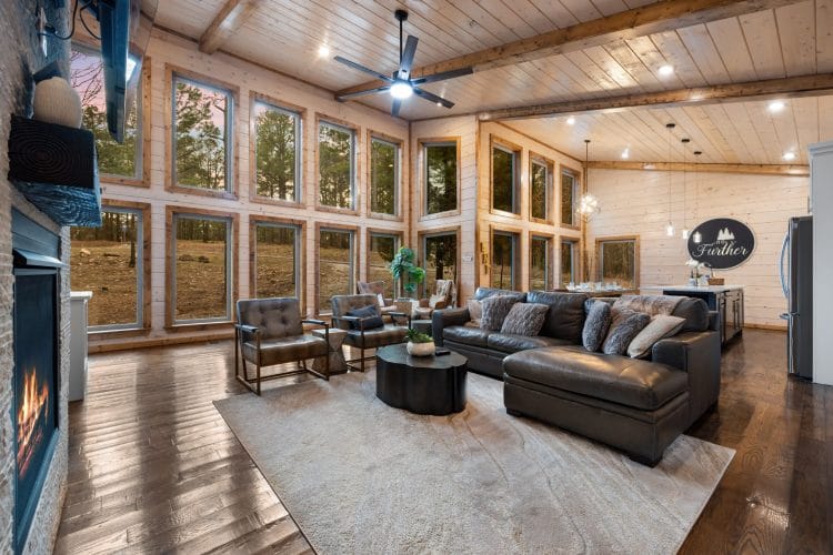 Living room with a gas fireplace, a dark leather sectional and a wall of tall windows