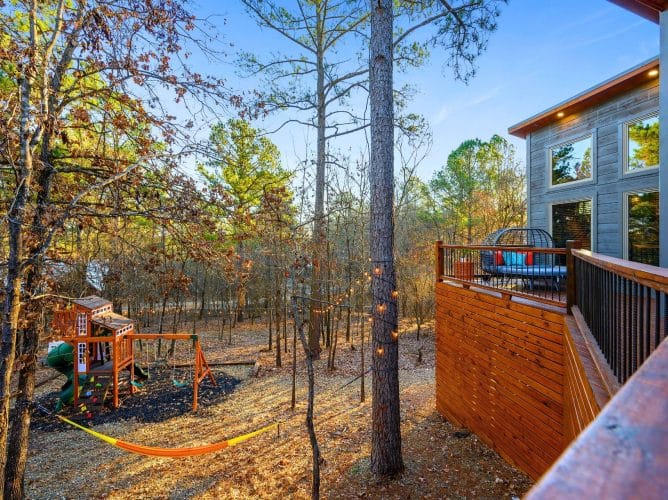 Playset and a hammock between trees with the deck at the right