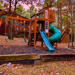 Playset with a spiral slide and swings on mulch
