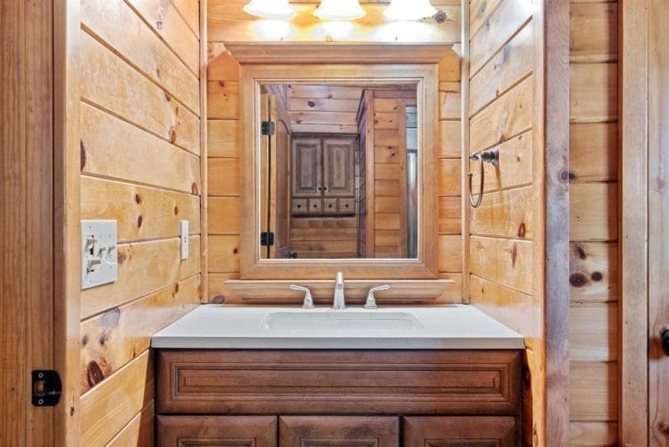 Bathroom with a white vanity and a framed mirror on pine walls