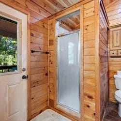 Bathroom with a toilet, a shower stall with a glass door and a window