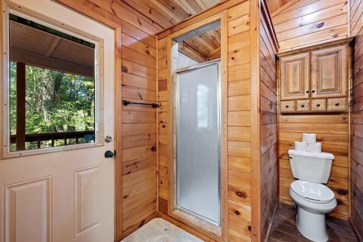 Bathroom with a toilet, a shower stall with a glass door and a window