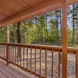 View along the covered porch railing out to the pine trees and gravel yard
