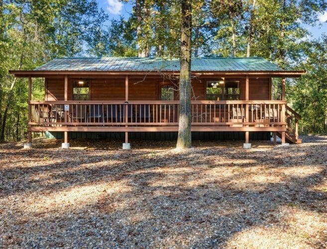 Wide view of the porch side of the cabin with a tree in front
