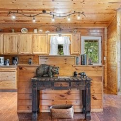 Kitchen with light wood cabinets, a black refrigerator and a dark wood console table, with the back door beside it