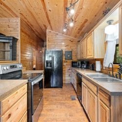 Galley run of the kitchen with a stainless range, a black refrigerator and a long counter