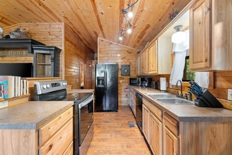 Galley run of the kitchen with a stainless range, a black refrigerator and a long counter