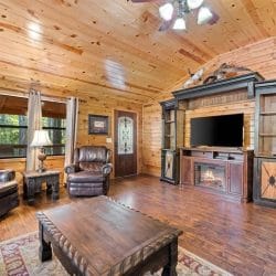 Living room with a TV on a wooden entertainment center, leather recliners and a wood coffee table