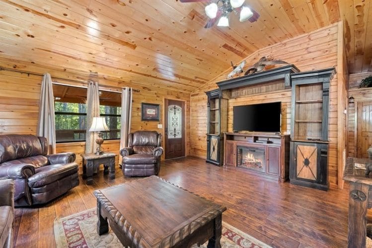 Living room with a TV on a wooden entertainment center, leather recliners and a wood coffee table
