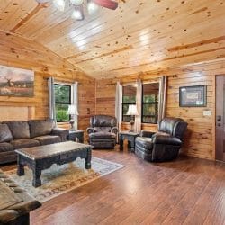 Leather sofa, recliners and a dark wood coffee table on a patterned rug, with the front door at right