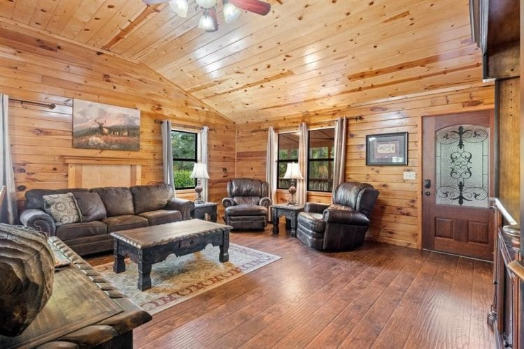 Leather sofa, recliners and a dark wood coffee table on a patterned rug, with the front door at right