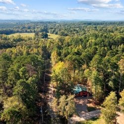Aerial view of forest and hills with the cabin just visible among the trees