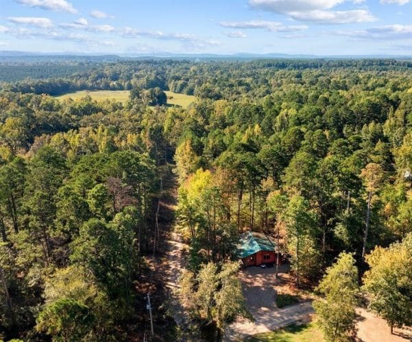 Aerial view of forest and hills with the cabin just visible among the trees