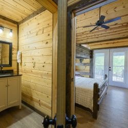 Bathroom vanity with a dark mirror beside a bunk bed and French doors