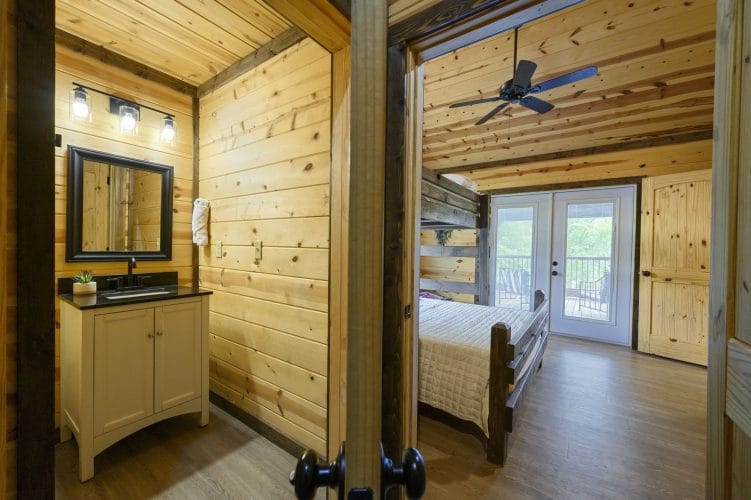 Bathroom vanity with a dark mirror beside a bunk bed and French doors