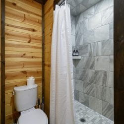 Tiled walk-in shower with a curtain and a toilet