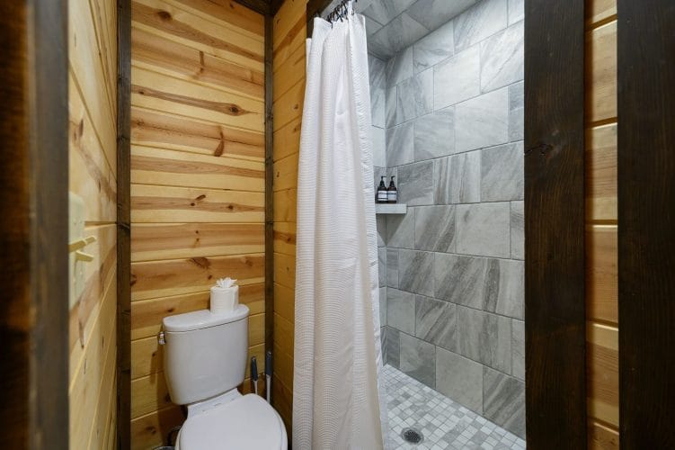 Tiled walk-in shower with a curtain and a toilet