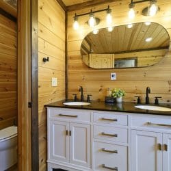 Double white vanity with black counters and an oval mirror