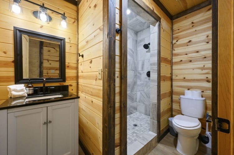 Vanity with a black-framed mirror and a walk-in shower, toilet at right