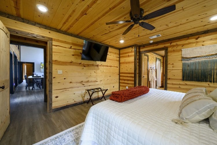 Same bedroom with a wall TV and a doorway toward the dining area