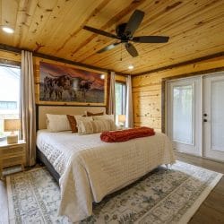 King bed with French doors to the porch and a ceiling fan