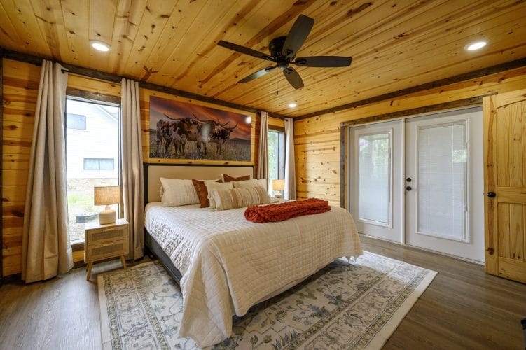 King bed with French doors to the porch and a ceiling fan