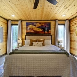 King bed with a sunset horse artwork, a ceiling fan and pine walls