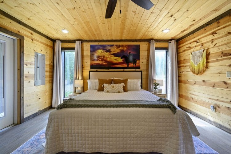 King bed with a sunset horse artwork, a ceiling fan and pine walls