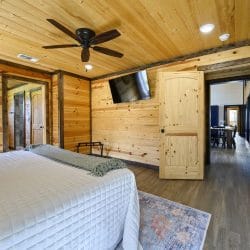King bedroom with a wall TV, a ceiling fan and a hall door