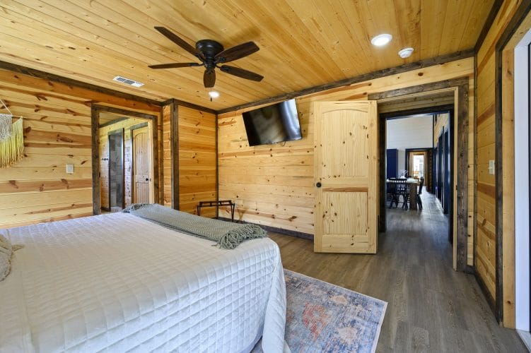 King bedroom with a wall TV, a ceiling fan and a hall door
