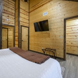 Bed with a wall TV and a luggage rack, a doorway beyond