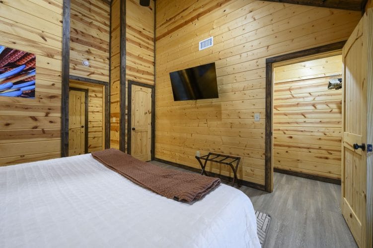 Bed with a wall TV and a luggage rack, a doorway beyond