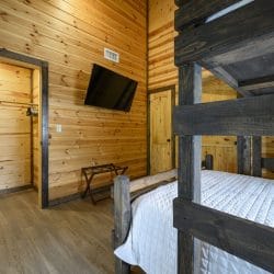 Bunk room with a wall TV, a luggage rack and a bunk frame in the foreground