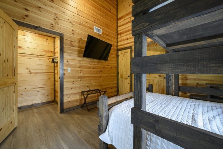 Bunk room with a wall TV, a luggage rack and a bunk frame in the foreground