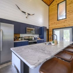 Kitchen with a stainless refrigerator, navy cabinets and an island with leather stools
