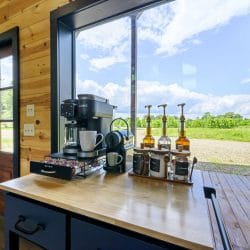 Coffee station by a window with a coffee maker and pod drawer, looking out over a field