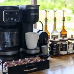 Keurig coffee maker with syrup bottles and canisters on a butcher-block counter