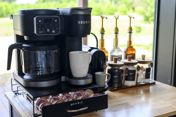 Keurig coffee maker with syrup bottles and canisters on a butcher-block counter